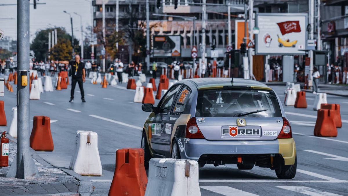 Modern automobile driving on asphalt road with barriers in street of contemporary town